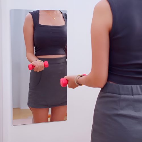 Vrouw met halters voor een lange rechthoekige acryl spiegel